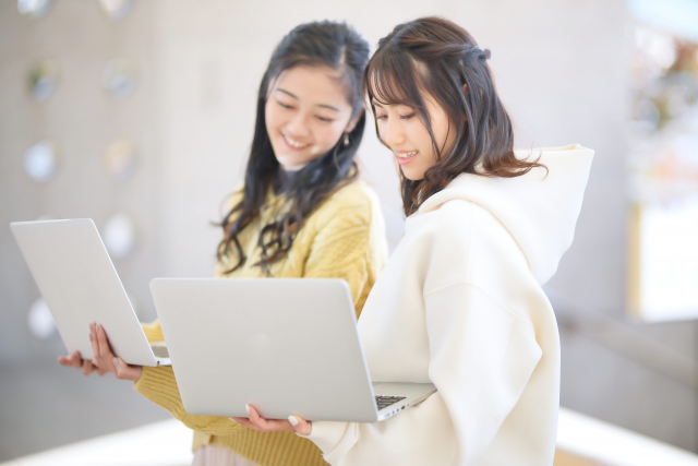 パソコンを見るパーカーの女性